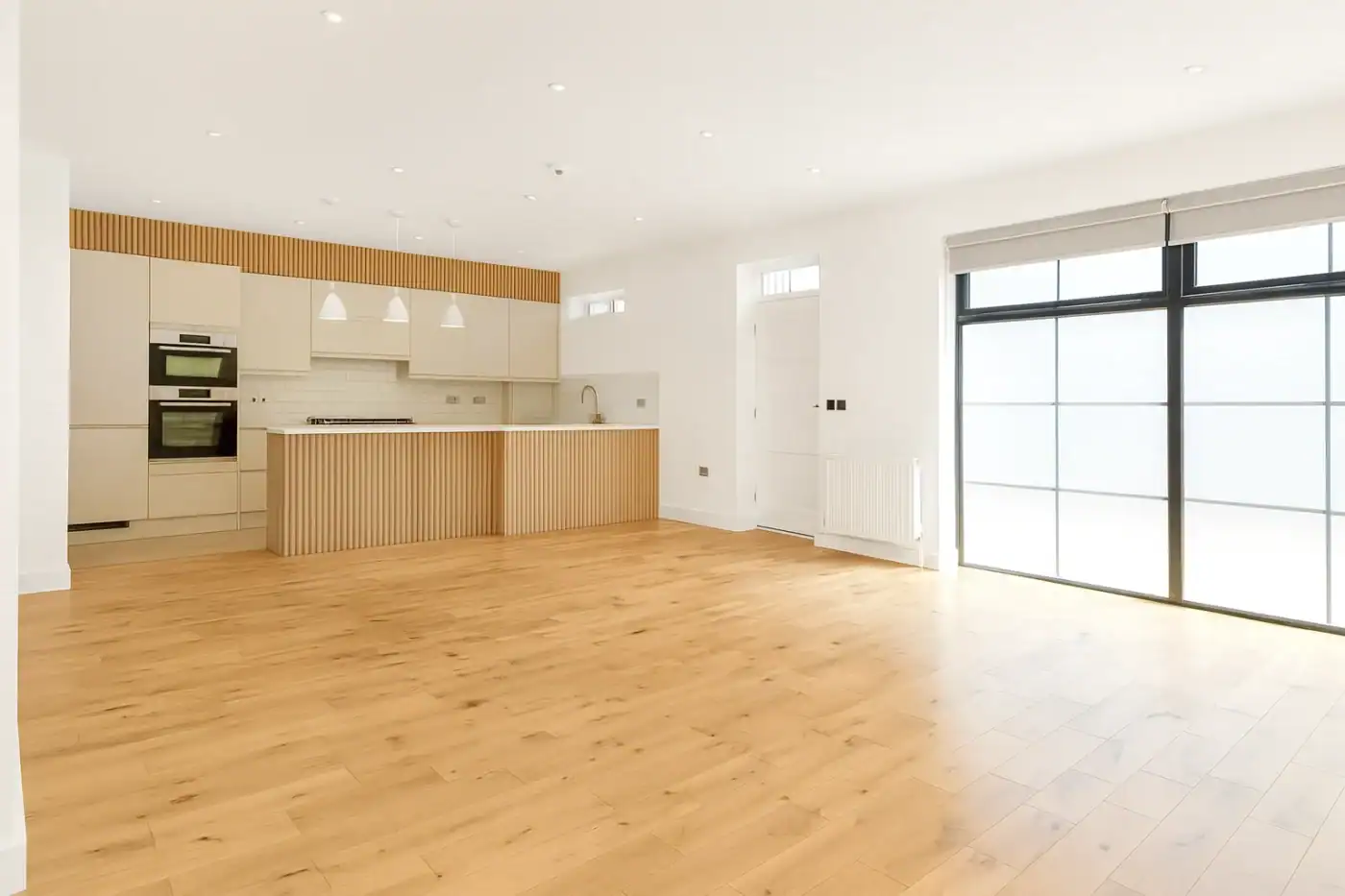 Spacious modern kitchen with natural wood flooring and large windows, perfect for contemporary home design. for a mansard roof loft conversion