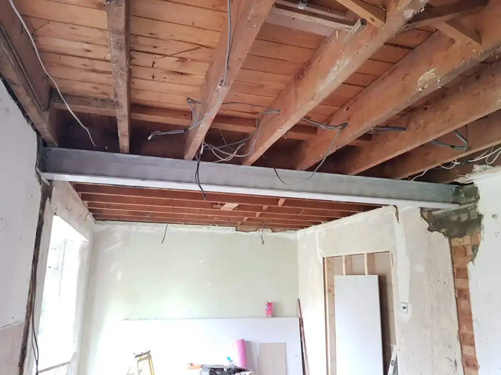 How to Identify a Load-Bearing Wall by the direction of the joist, this image show Steel beam inserted to remove a load bearing wall at first floor, steel to support floor joist